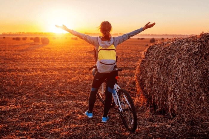 Cyclist in field watching sunset