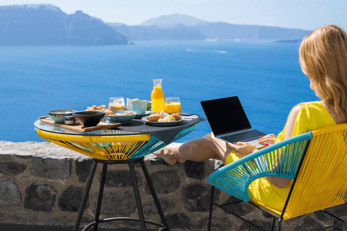 Woman holidaying with breakfast and laptop