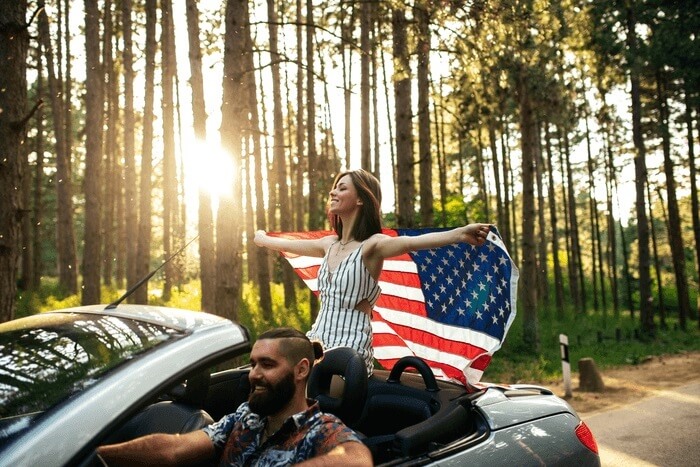 Lady flying American flag in open top car