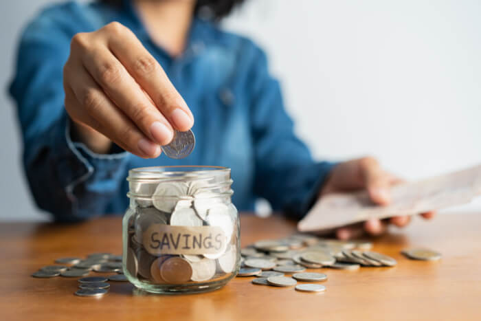 Woman putting loose change into savings jar