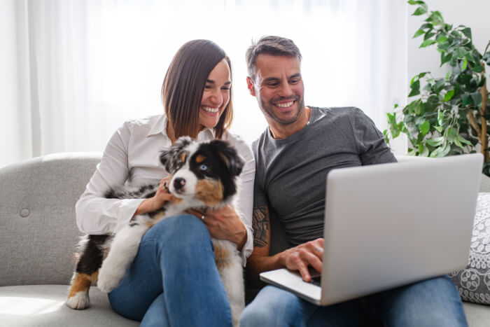 Couple using laptop with puppy