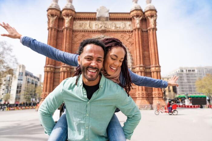 Woman piggybacking on man at Arc de Triomf in Barcelona