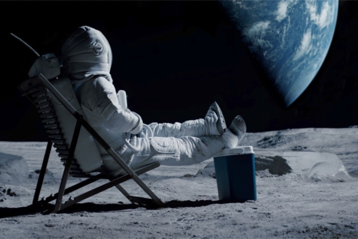 Astronaut relaxing on the moon, looking off to earth